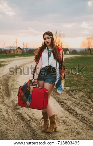Hipster girl standing on a dirt road.