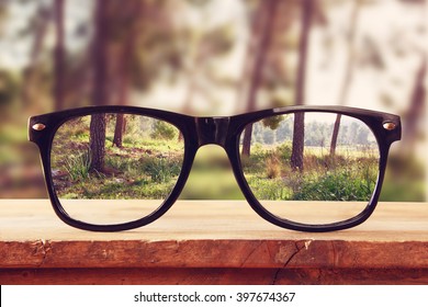 битник очки на деревянном деревенском столе перед лесом. старинные фильтрованные