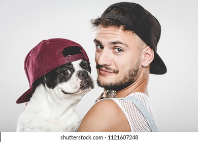 Hipster guy hugging his nice French Bulldog dog against neutral background - Powered by Shutterstock