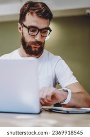  hipster guy in spectacles checking time planning schedule using netbook for studying
