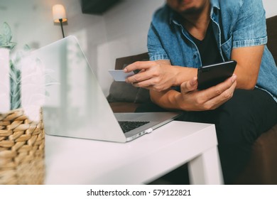 hipster hand using smart phone and laptop computer,holding credit card payments online business,sitting on sofa in living room,green apples in wooden tray,filter