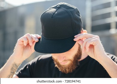 Hipster handsome male model with beard wearing black blank baseball cap  with space for your logo