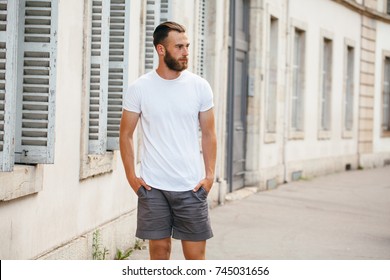 Hipster Handsome Male Model With Beard Wearing White Blank T-shirt With Space For Your Logo Or Design In Casual Urban Style