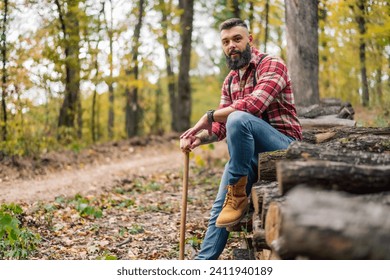 A hipster lumberjack relaxes on the pile of freshly cut logs, pausing for a portrait. - Powered by Shutterstock