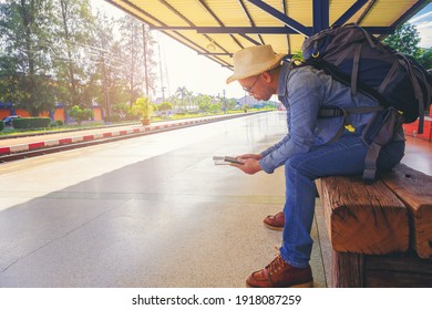 Hipster man with backpack waiting the train at train station for travel in the morning. Travel by train concept.