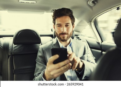 Hipster Man In Car. Typing Text Message On Mobile Phone. Filter Vintage