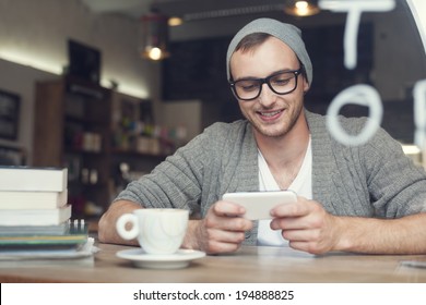 Hipster Man With Mobile Phone At Cafe  