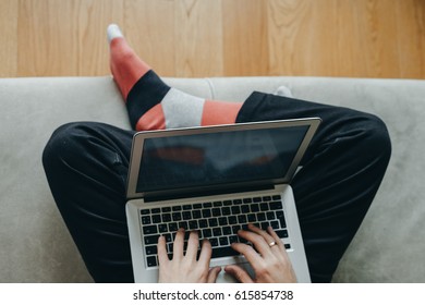 Hipster Man In Red Socks Working At Laptop  On The Couch