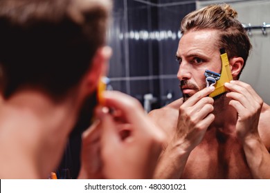 Hipster Man Shaving His Beard In The Bathroom