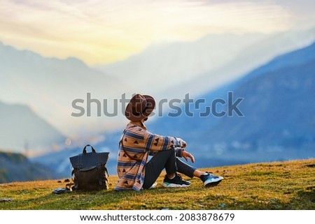 Hipster man traveler wanderer wearing hat sitting alone and enjoying freedom and calm inspired travelling 