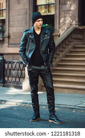 Hipster Man Wearing Black Style Leather Outfit With Hat, Pants, Jacket And Shoes Standing On City Street 