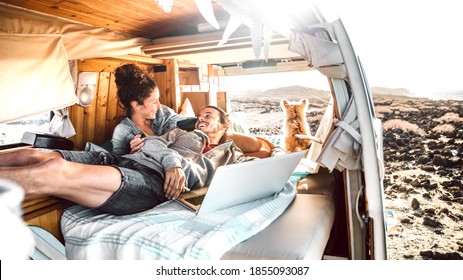 Hipster man and woman with dog traveling together on mini van transport - Freelance nomad concept with indie people on minivan romantic trip working at laptop pc in relax moment - Warm retro filter