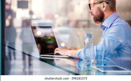 Hipster Manager In Cafe, Working On Laptop By Window