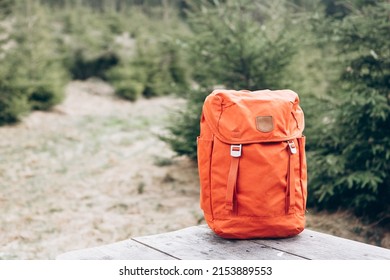 Hipster orange backpack. View from front tourist traveler bag with forest background. Travel outdoor concept