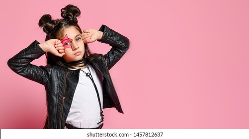 hipster punk girl - dressed in a leather jacket and skirt, black knee-highs and a white T-shirt, with a funny hairstyle and a makeup painted star on the face, points to the head
