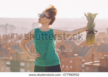 hipster red hair woman holding a pineapple with glasses.
