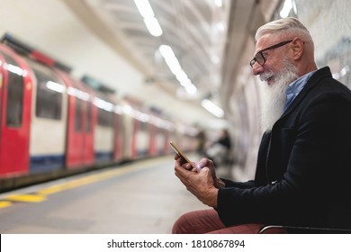 Hipster senior man chatting on his smartphone while waits for subway train - Mature man having fun with technology trends - Tech elderly joyful night concept - focus on face and hand