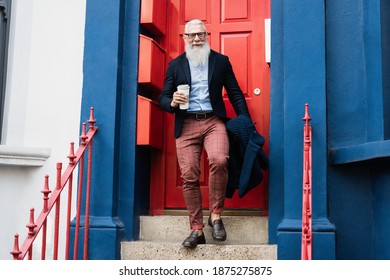 Hipster Senior Man Drinking Coffee While Walking Out From Home - Focus On Face