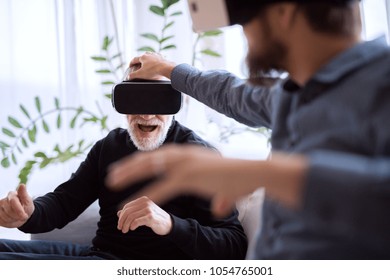 Hipster son and his senior father with VR goggles at home. - Powered by Shutterstock