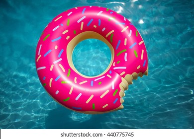 Hipster sprinkled donut float in sunny pool background straight down on bright clear pool water