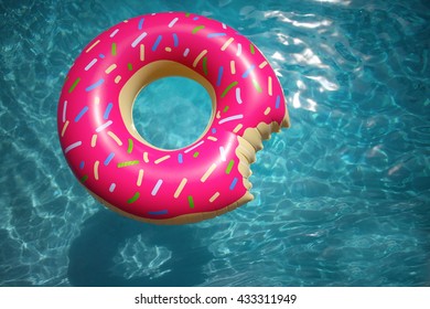 Hipster sprinkled doughnut float in sunny pool background at a slight angle