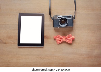 Hipster style. Overhead of objects on wooden background. Concept of the photographer. retro camera, digital tablet, bowtie.