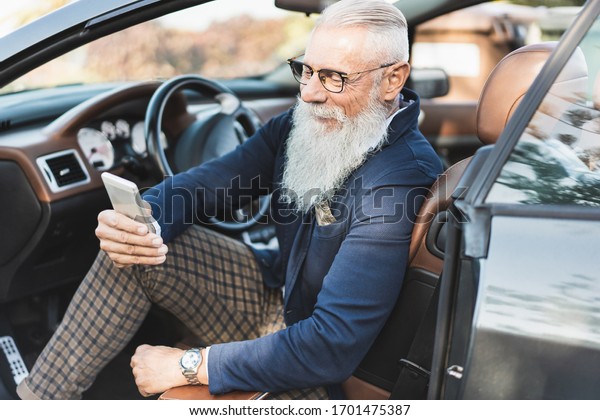  Hipster stylish man looking his smartphone\
in convertible car - Senior sitting in cabriolet auto - Fashion and\
elegant businessman
