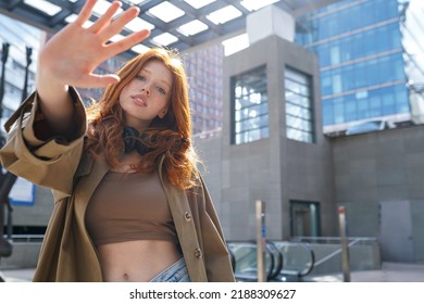 Hipster teen stylish redhead fashion girl model posing in big city urban location. Beautiful teenage generation z girl with red hair wearing trench coat looking at camera. Portrait - Shutterstock ID 2188309627