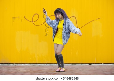 hipster teenager with afro hair  dancing to music on a yellow background