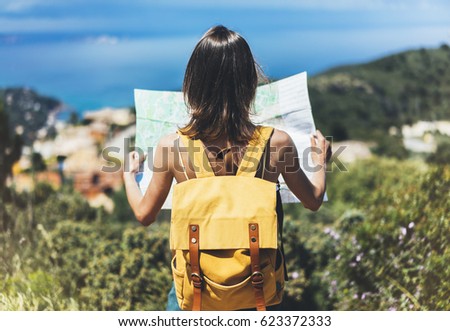 Hipster tourist hold and look map on trip, lifestyle concept adventure, traveler with backpack on background mountain and blue sea landscape horizon, young girl hiker pointing hands on trekking plan