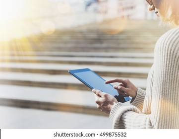 Hipster Tourist Texting Message On Tablet Or Technology Mock Up. Person Using Computer On Building Background Close. Female Hands Holding Gadget On Blurred Backdrop Mockup. Copy Space, Flare