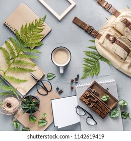 Hipster travel objects flatlay with book, plants, leaves, glasses, cards, coffee cup, frame. Creative work table for photographer, traveller, blogger. Working space surface top view