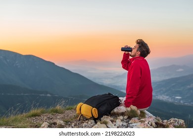 A hipster traveler man with a backpack is resting while drinking a water from a bottle during the hike on the mountain top at sunrise active healthy lifestyle. - Powered by Shutterstock