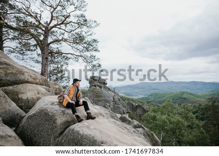 Hipster treveler standing alone on the edge cliff mountain and looking away. Adventure vacation, text spase