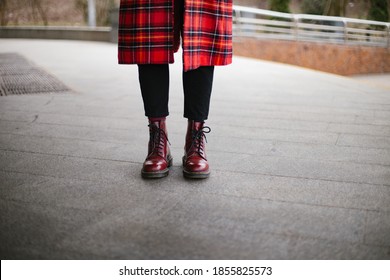 Hipster wearing red trendy boots and coat trench gray background