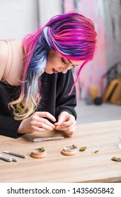hipster woman with colorful hair rolling joint from medical marijuana while sitting at table 