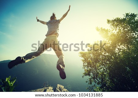 hipster woman hiker jumping on cliff's edge