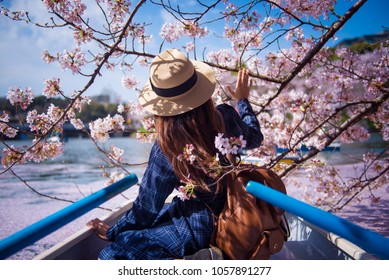 Hipster woman is sightseeing cherry blossom on the row boat while traveling during spring season at Chidorigafuchi boat parking inside the Kitanomaru Park in Tokyo, Japan.