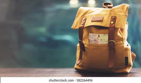 Hipster yellow backpack and map closeup. View from front tourist traveler bag on background blue sea aquarium. Person hiker visiting ocean museum in Barcelona on backdrop, blank blurred mock up