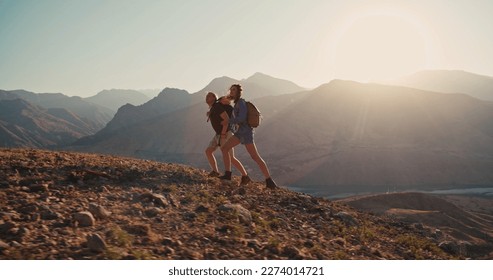 Hipster young couple with backpack enjoying sunset on peak of foggy mountain. Young caucasian couple backpacking together, exploring beautiful mountains - adventure, freedom concept - Powered by Shutterstock