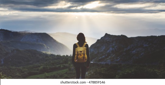 Hipster young girl with backpack enjoying sunset on peak mountain. Tourist traveler on background valley landscape view mockup. Hiker looking sunlight flare in trip in Spain basque country Europa - Powered by Shutterstock