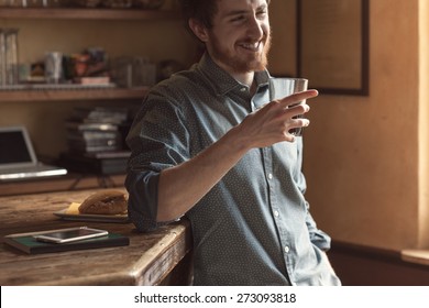 Hipster Young Smiling Man Drinking A Glass Of Coke And Leaning On A Wooden Table