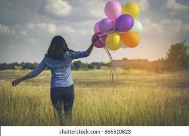 The hipsters Asian pretty girl holding colorful balloons on the meadow green.