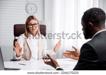 Hiring, interview. Refusal to work due to racism. Business woman refuses to hire an African American. He throws up his hands and looks dismissively.