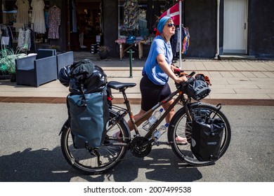 Hirtshals, Denmark July 5, 2021 A Long Distance Bicyclist Walking Her Bike On Main Street With Packs.