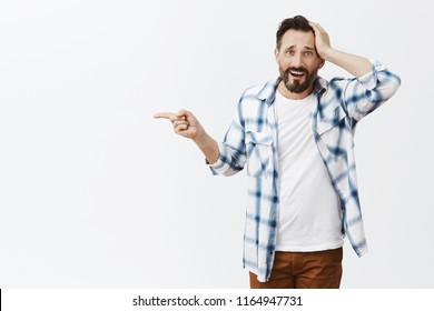 His Car Broke Down, Guy Asking Stranger Take Him To Gas Station. Portrait Of Upset Helpless Handsome Man With Beards, Pointing Left With Index Finger And Holding Palm On Head, Being In Tough Situation