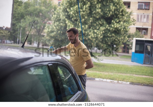 His car is\
important for him. Man washing\
car.