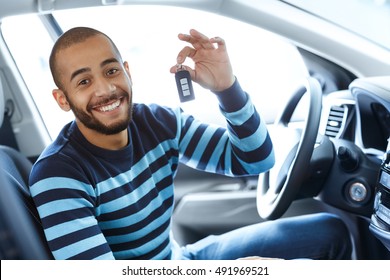 His dream day. Portrait of a handsome African man smiling excitedly while sitting in his newly bought car showing car keys to the viewer 