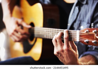 His skill has been gained through hours of practice. Cropped view of masculine hands strumming a guitar.