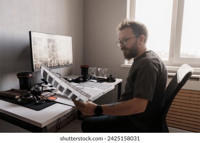 In his studio, a meticulous photographer reviews film negatives, ensuring each frame captures the envisioned artistic detail - Powered by Shutterstock